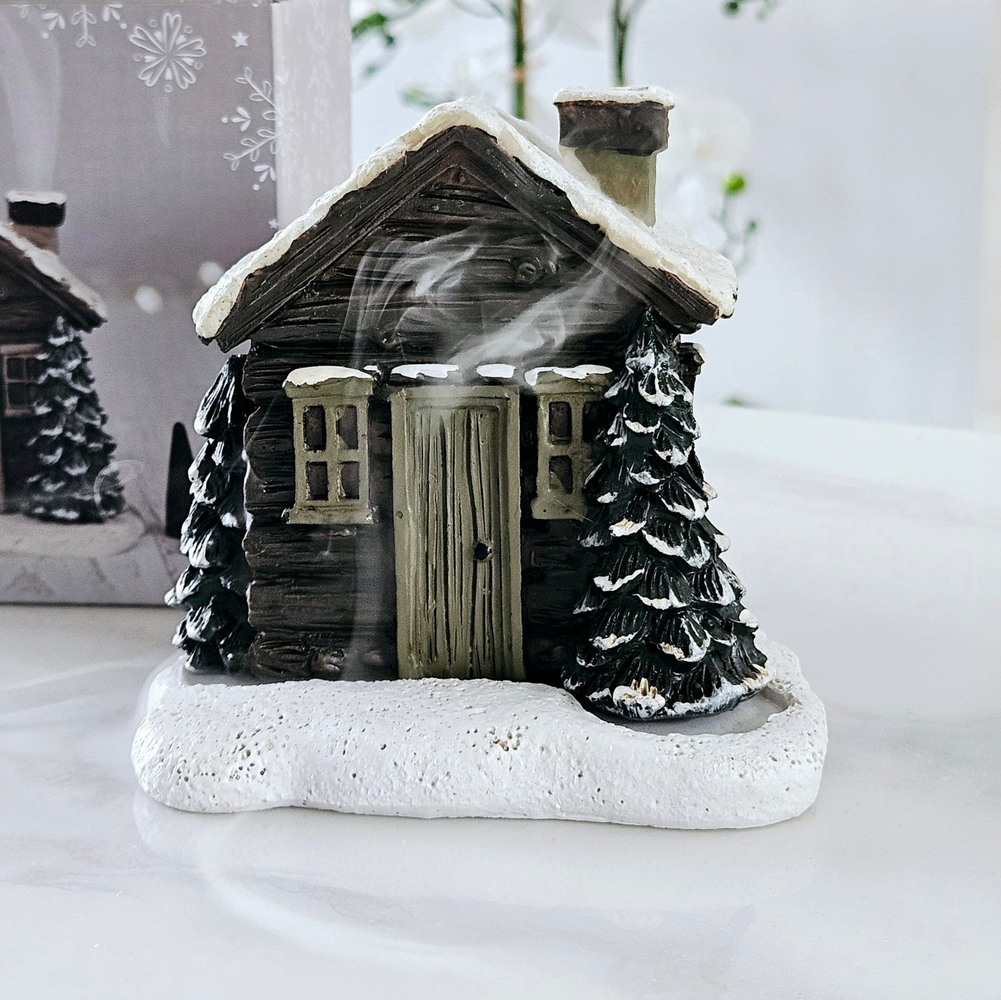 Log cabin house incense cone burner with smoked chimney and brown trees out front