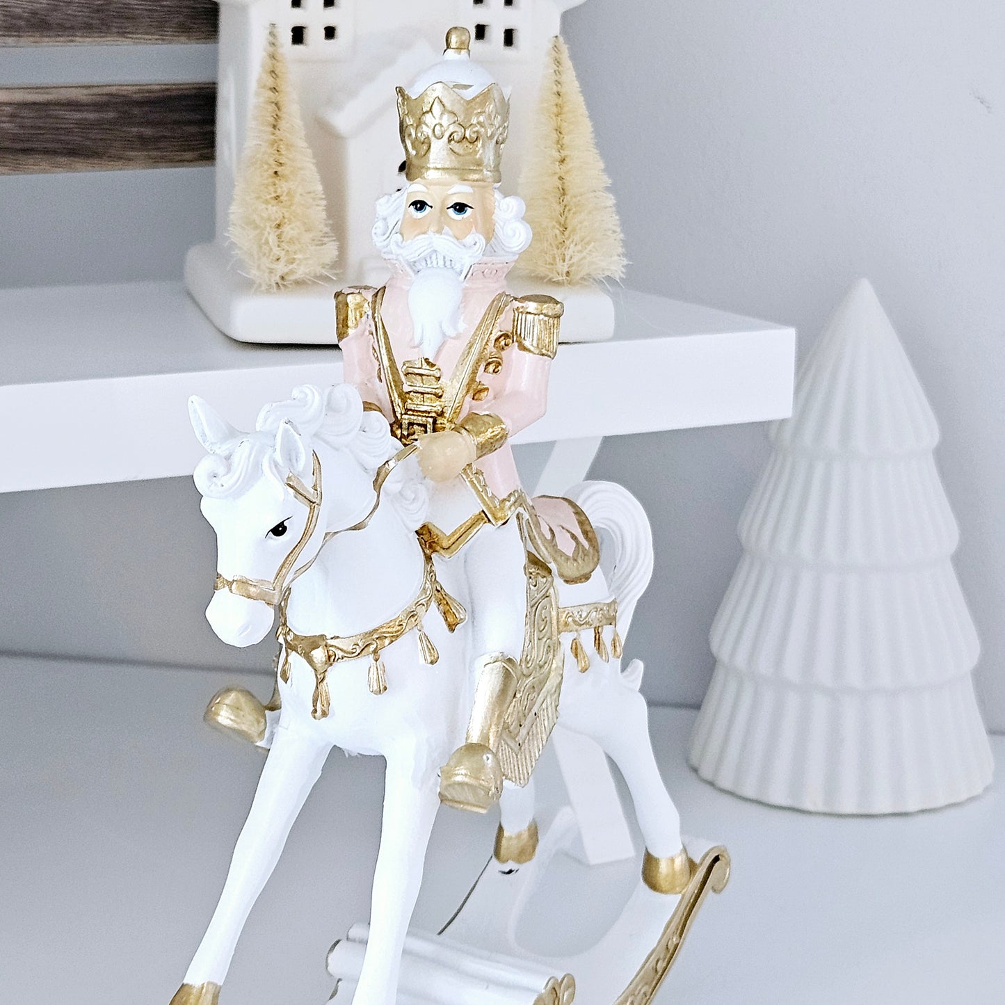 pink and gold nutcracker ornament sitting on a rocking horse