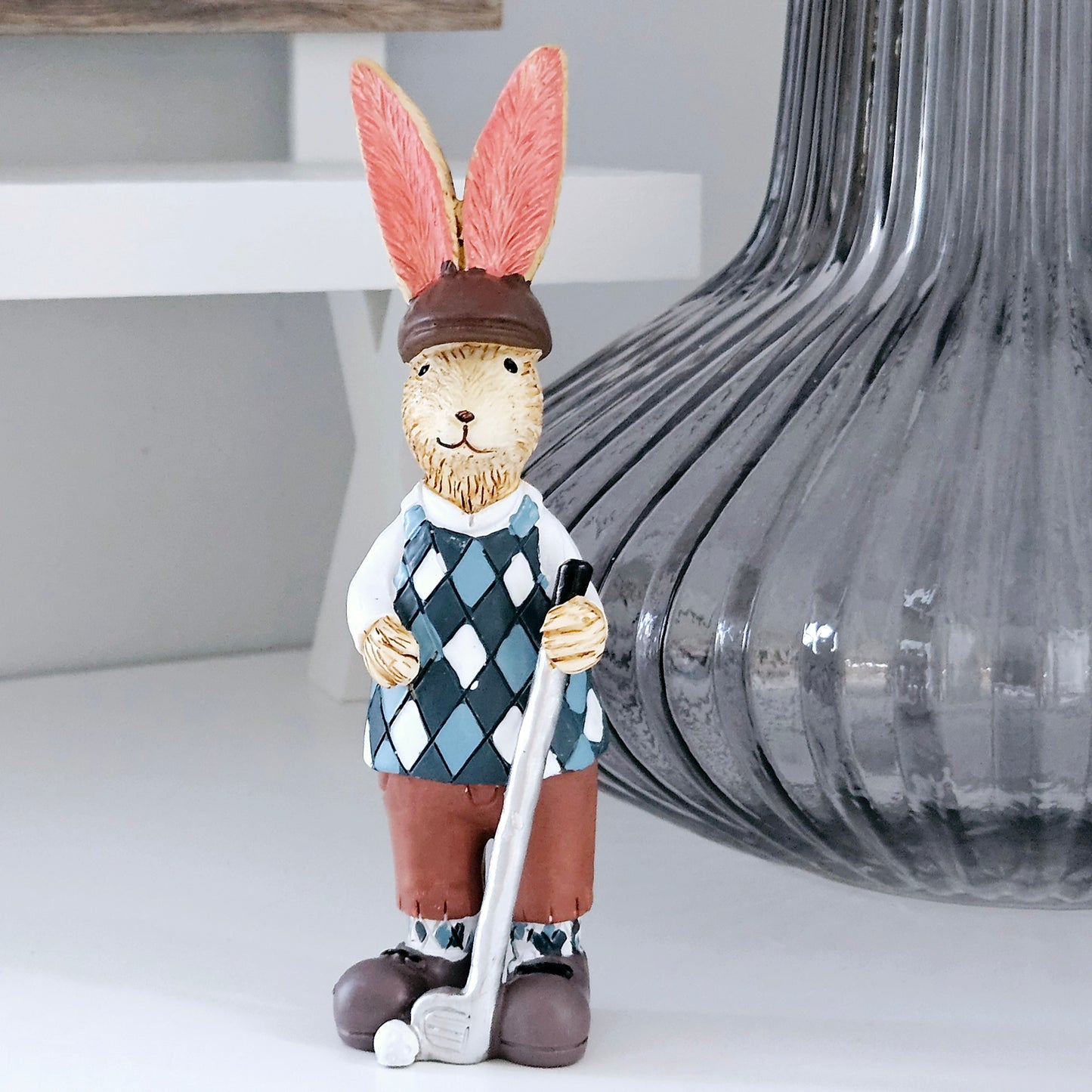 jasper rabbit playing golf holding a club and golf ball wearing chequered top