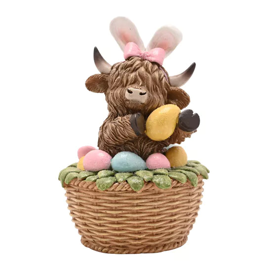 Figurine of a highland cow with bunny ears and Easter eggs in a basket