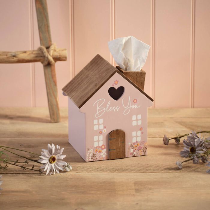 Wood tissue box in the shape of a house with a brown roof, pink sides, white windows, floral designs, heart cutout, and "Bless You" text on the front.