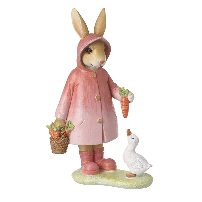 Figurine of a rabbit in a pink raincoat holding carrots and a basket, with a duck beside it