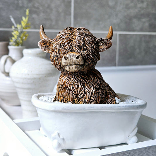 Highland cow ornament sitting in a white bath tub with bubbles