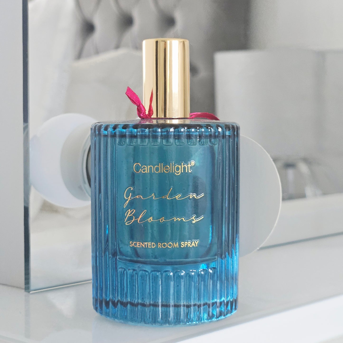 Blue scented room spray bottle with floral design and 'Candlelight Garden Blooms' label