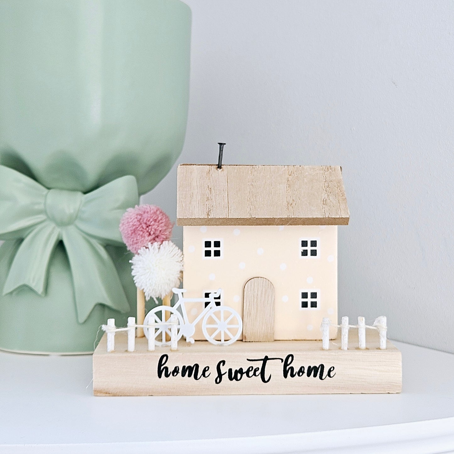 Home sweet home house block decoration with pink and white pom pom trees and a white bicycle and picket fence