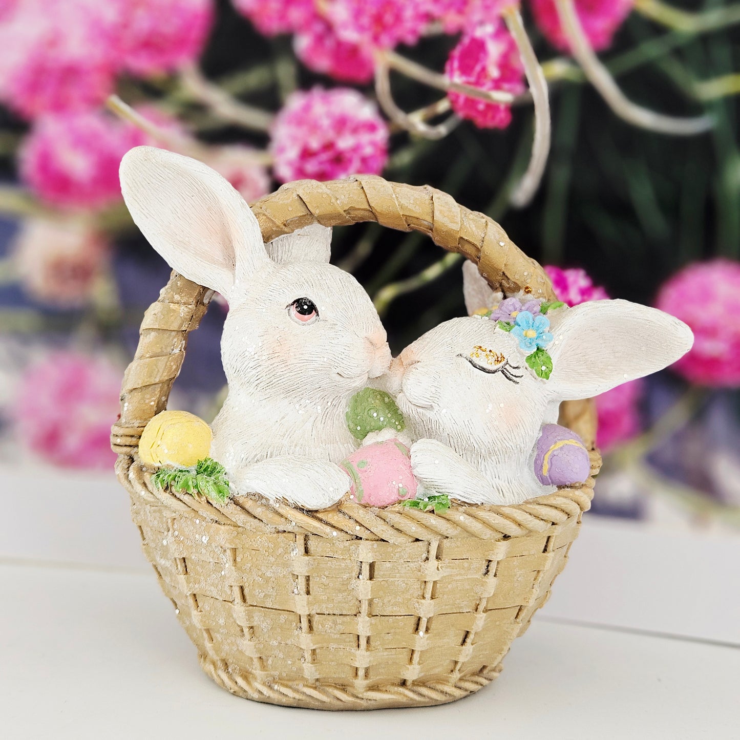 Decorative figurines of two rabbits in a basket with Easter eggs snuggled up