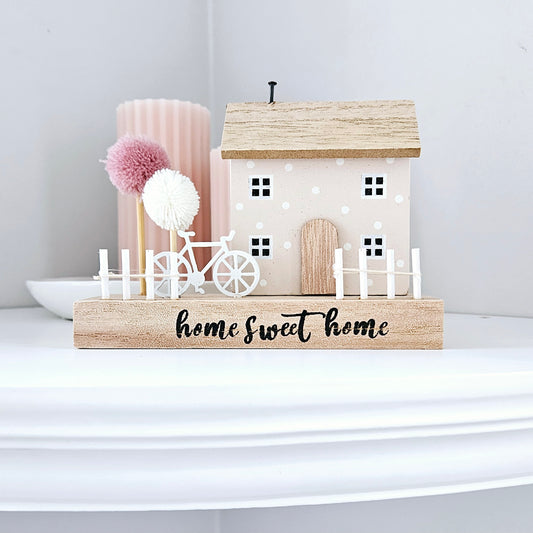 Home sweet home house block decoration with pink and white pom pom trees and a white bicycle and picket fence