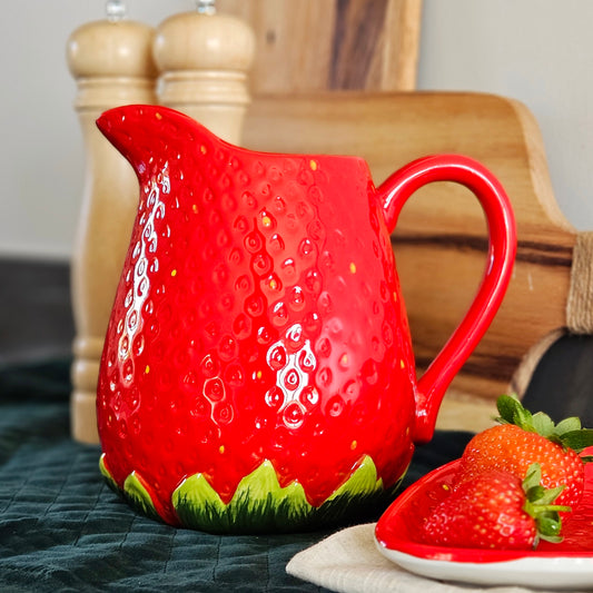 Red strawberry jug with green bottom and pitted seeds detail by cottage garden