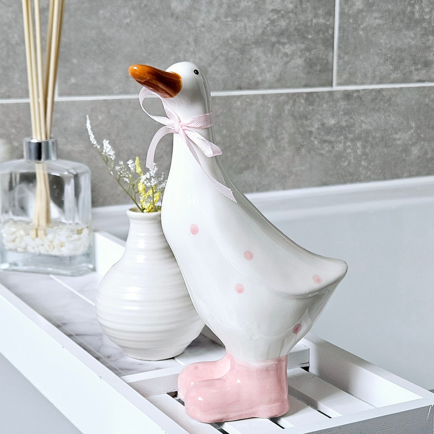 Large ceramic duck with pink polka dot spots and pink feet and jute bow