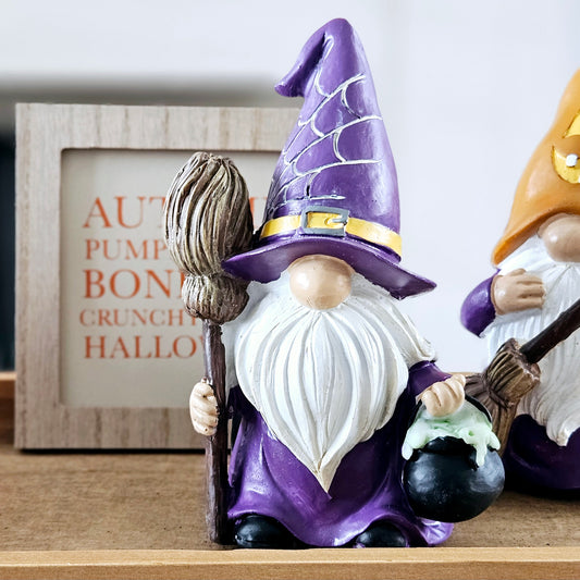 gnome dressed in purple holing a cauldron and broom with cob web purple hat ornament 