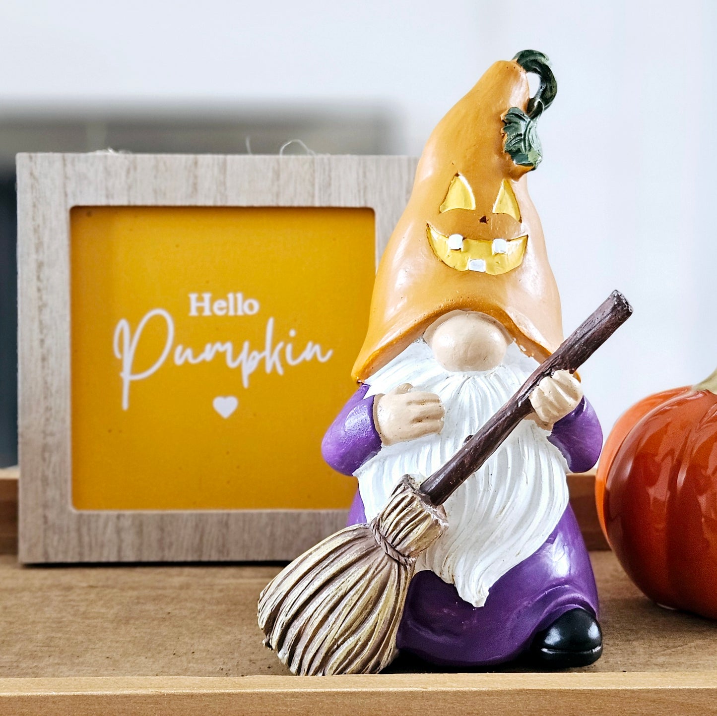 halloween ornament gnome holding a broom stick dressed in purple with an orange hat