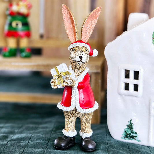 santa bunny ornament dressed in red holding a white and gold present 