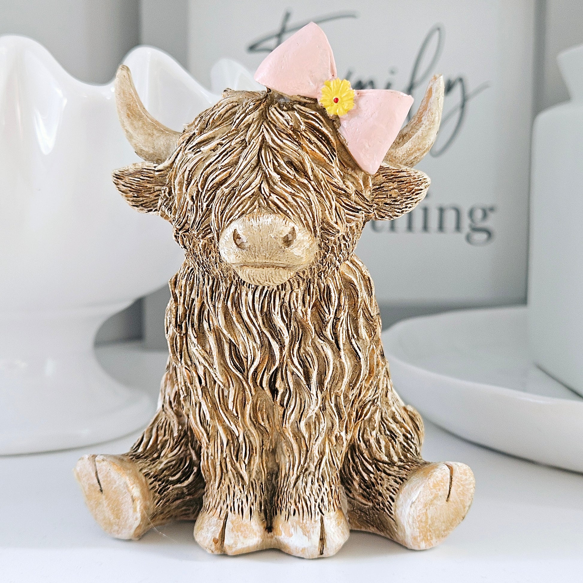 Highland cow with pink bow and yellow flower ornament