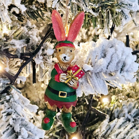 jasper bunny dressed as an elf with hanging string holding a red and gold present 