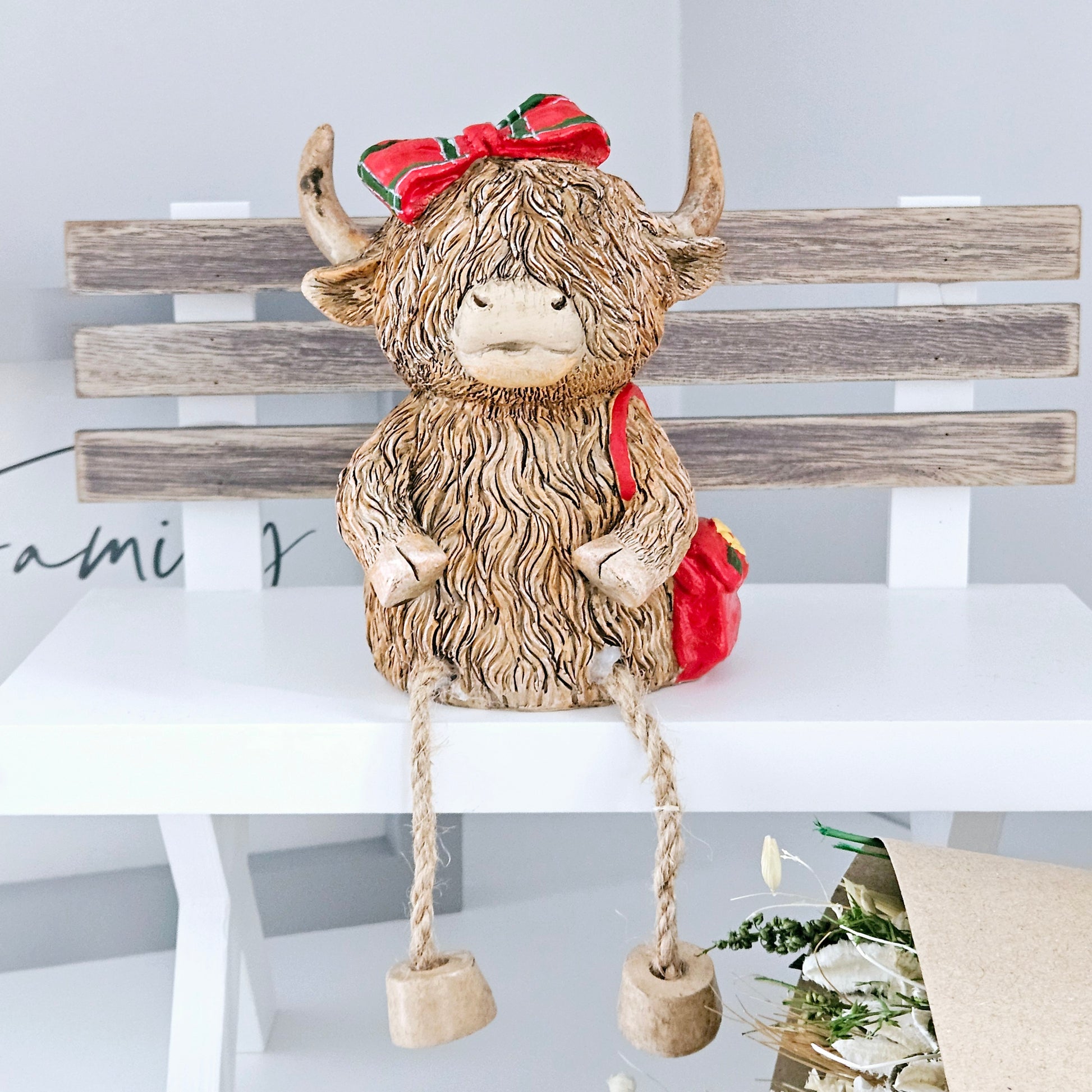 Highland cow Ornament sitting money box wearing a red tartan bow and red handbag 