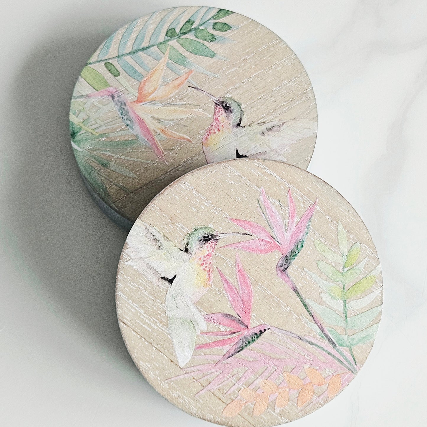 Two round chunky hummingbird coasters with bird and leaf designs 