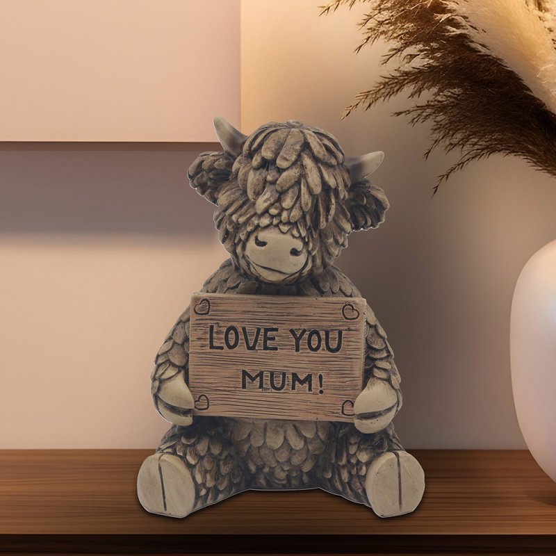 Decorative figurine of a cow holding a sign saying 'LOVE YOU MUM!' 