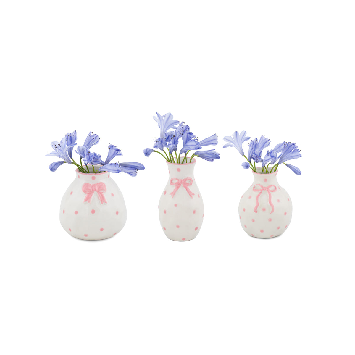 Three small white vases with pink polka dots and bows,