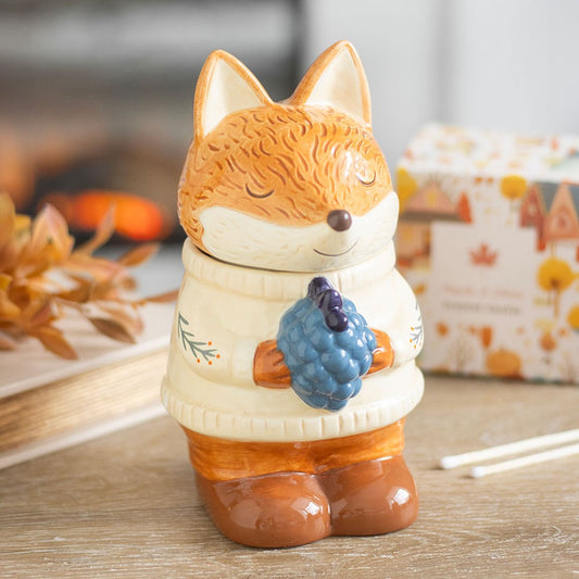 Ceramic fox-shaped wax warmer and oil burner with a white sweater holding blueberries 