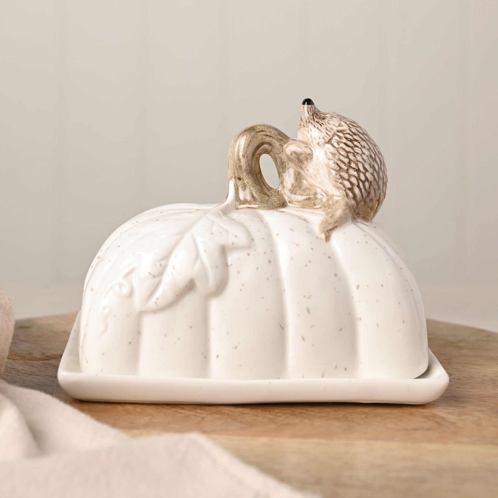 hedgehog butter dish with leaf and brown speckles on a white ceramic