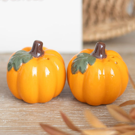 Two ceramic pumpkin-shaped salt and pepper shakers with stem and leaf