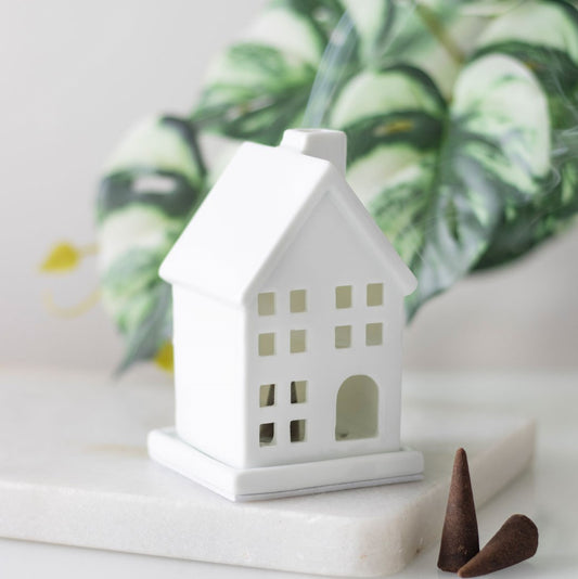White house-shaped incense holder with smoke coming from chimney 