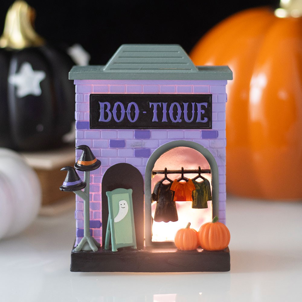 Halloween-themed boutique with lit interior, pumpkins, and ghost decorations.