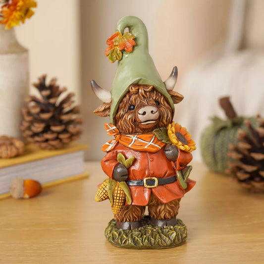 Decorative figurine of a Highland cow in a green hat with autumn decorations holding corn on the cob and sunflower