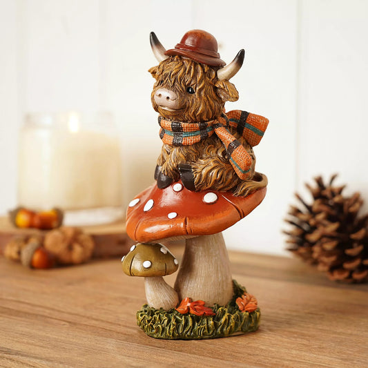 Decorative figurine of a cow with a hat and scarf on a mushroom