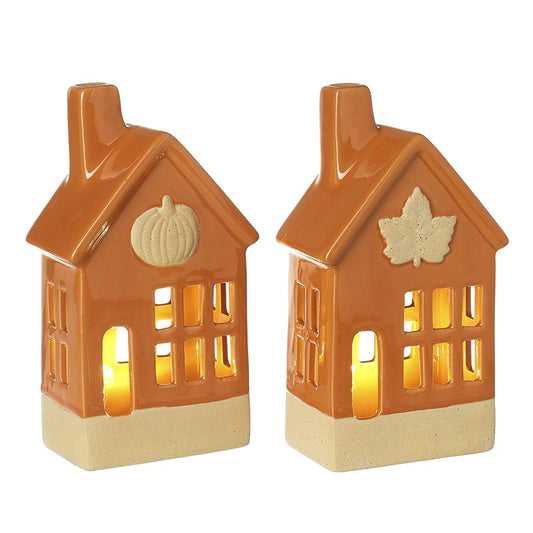 Two orange ceramic house-shaped led lanterns with pumpkin and leaf designs