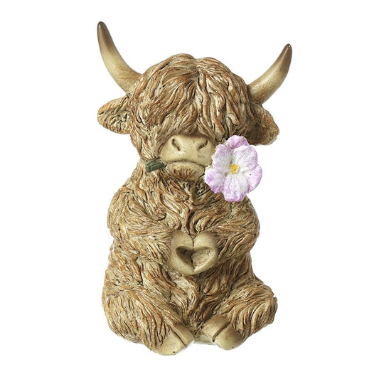 Statue of a highland cow with a flowering its mouth making a heart shape with paws