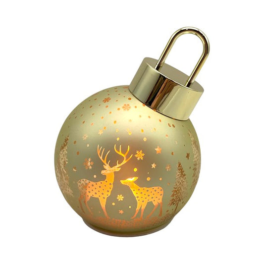 A spherical Christmas ornament-style lamp with a gold-toned metal cap and loop, glowing warm yellow inside. The frosted surface is decorated with etched deer, stars, and snowflakes, showing a golden holiday scene.