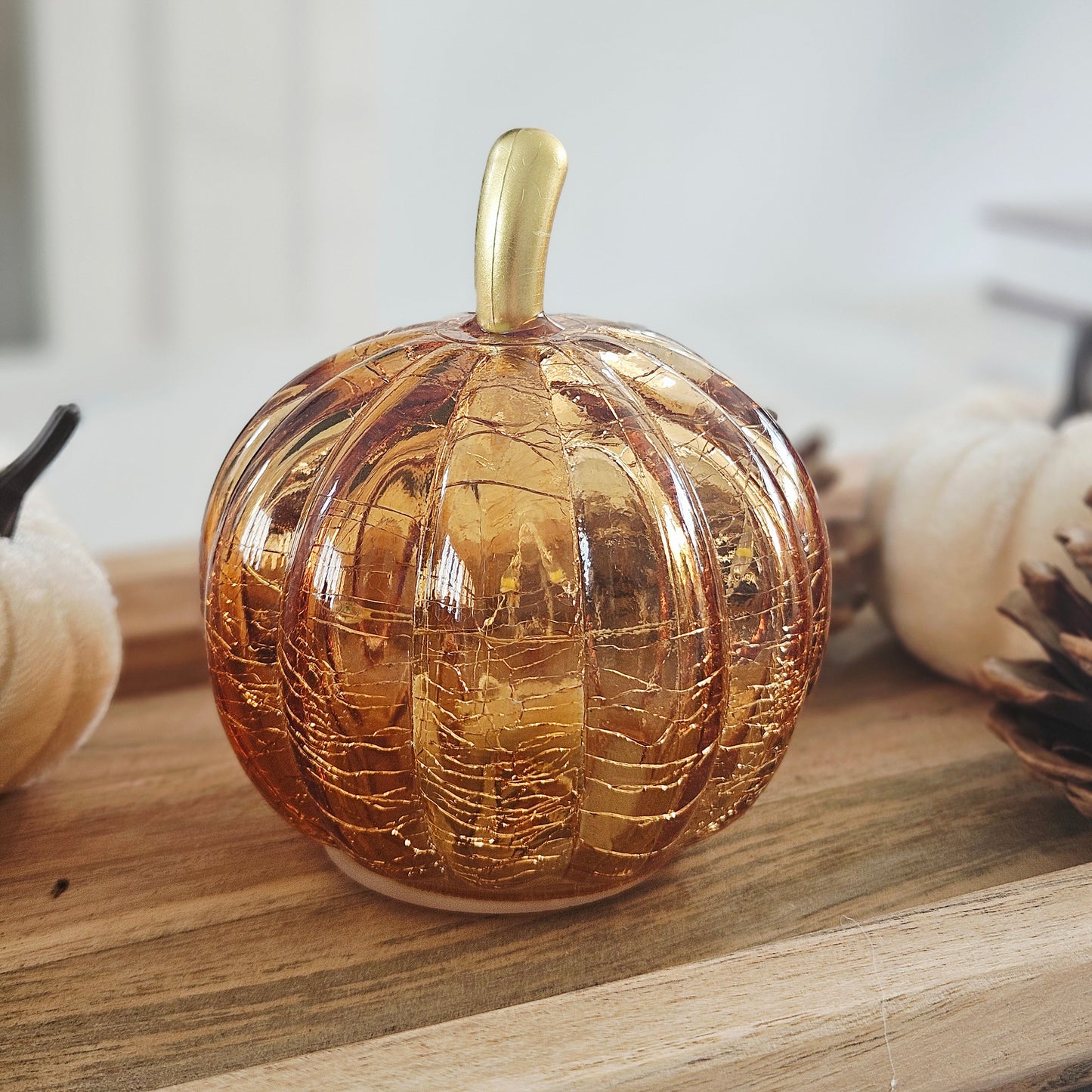 A small decorative led glass pumpkin-shaped vessel with a glossy amber-gold finish and a matching gold stem