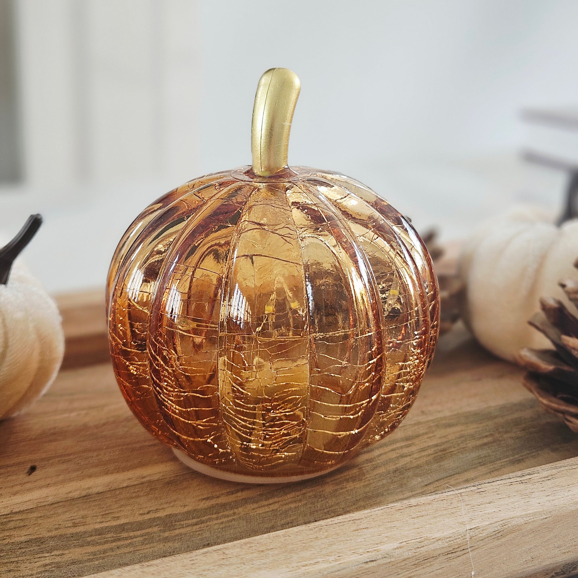 A small decorative led glass pumpkin-shaped vessel with a glossy amber-gold finish and a matching gold stem