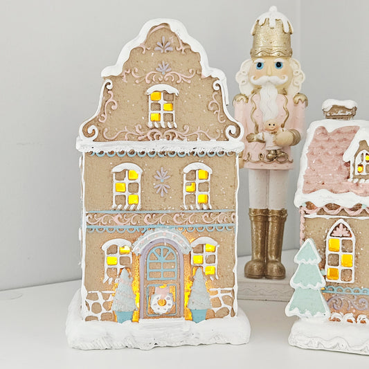 Decorative gingerbread house-shaped light with gold and white design and pastel colours