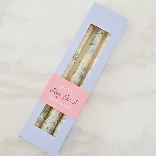 Set of three floral taper candles in a box with a pink label on a light gray background