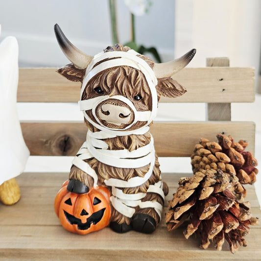 highland cow ornament dressed as a mummy with foot on a pumpkin 13cm