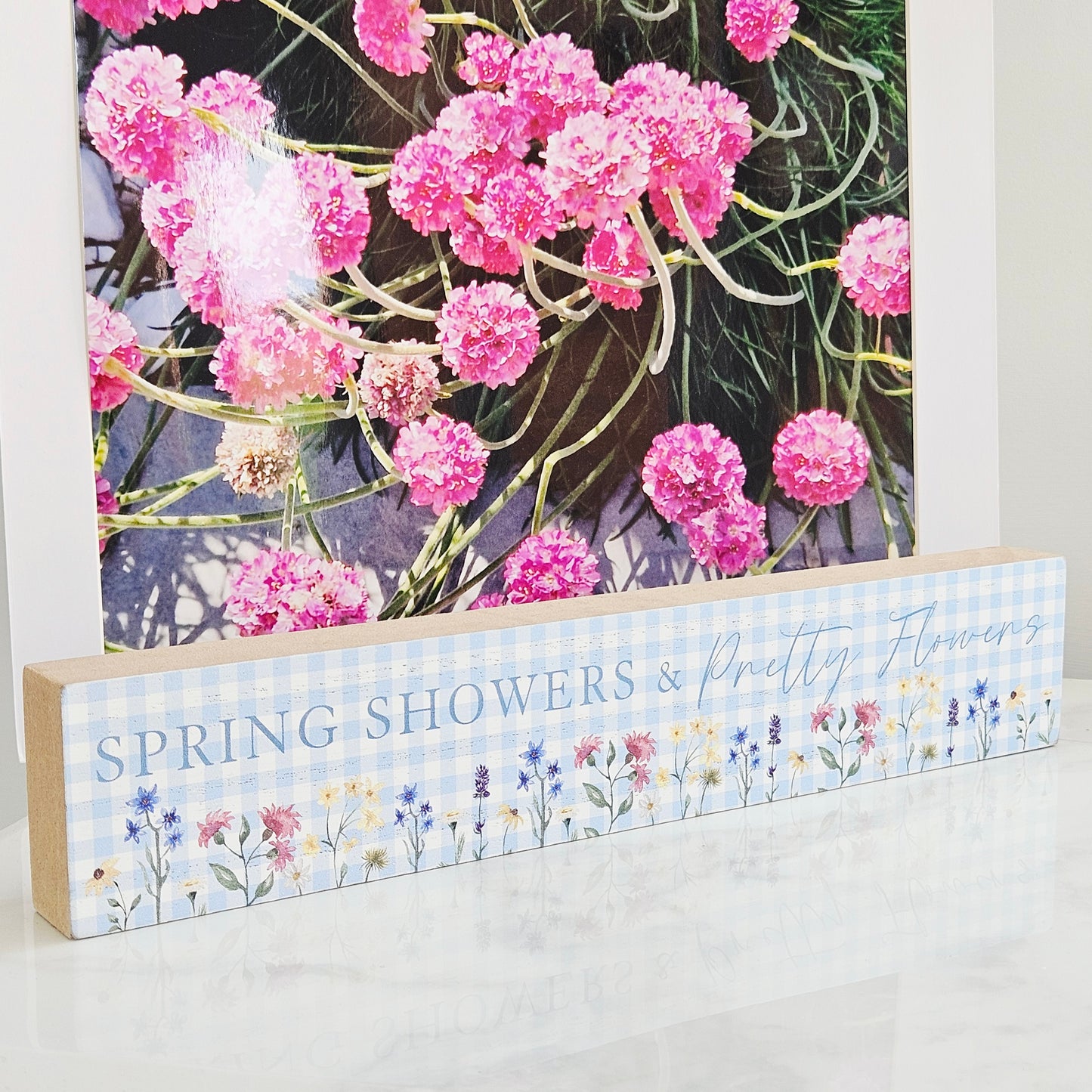 Decorative mantel plaque with 'Spring Showers & Pretty Flowers' text and floral design on a blue checkered gingham background.