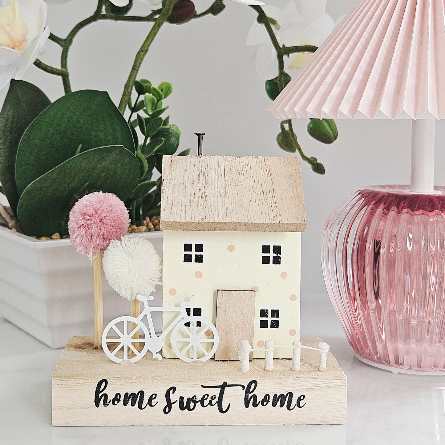Home sweet home house block decoration with pink and white pom pom trees and a white bicycle and picket fence