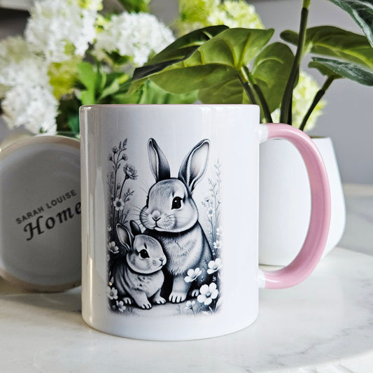 White mug with pink handle featuring black and white rabbit illustration and flowers