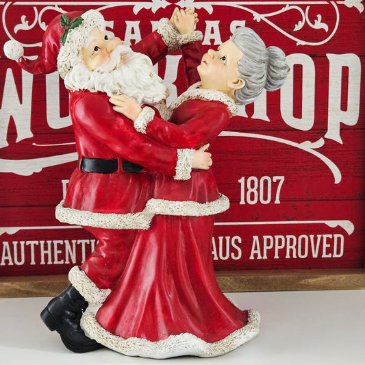 Decorative figurine of a mr & Mrs Claus in red attire dancing together hand in hand