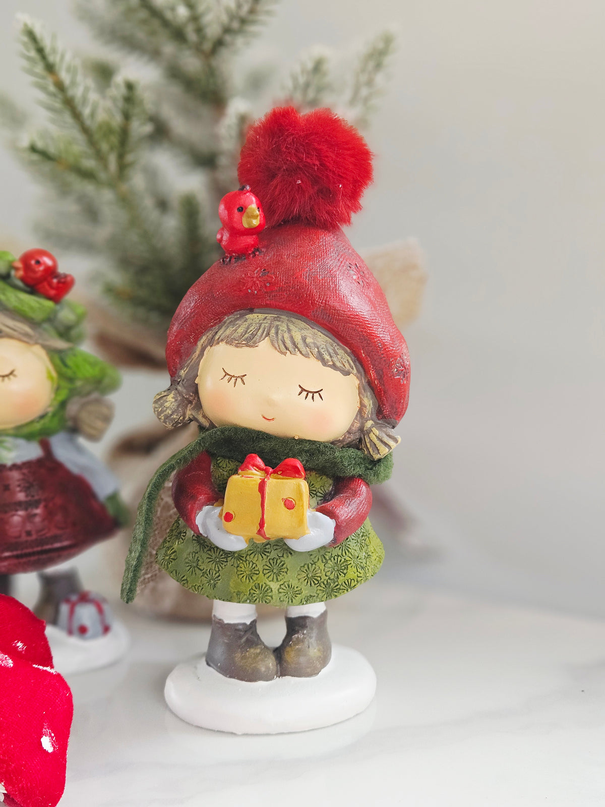 Woodland Noel standing resin Christmas girl holding gift with scarf and pom pom hat