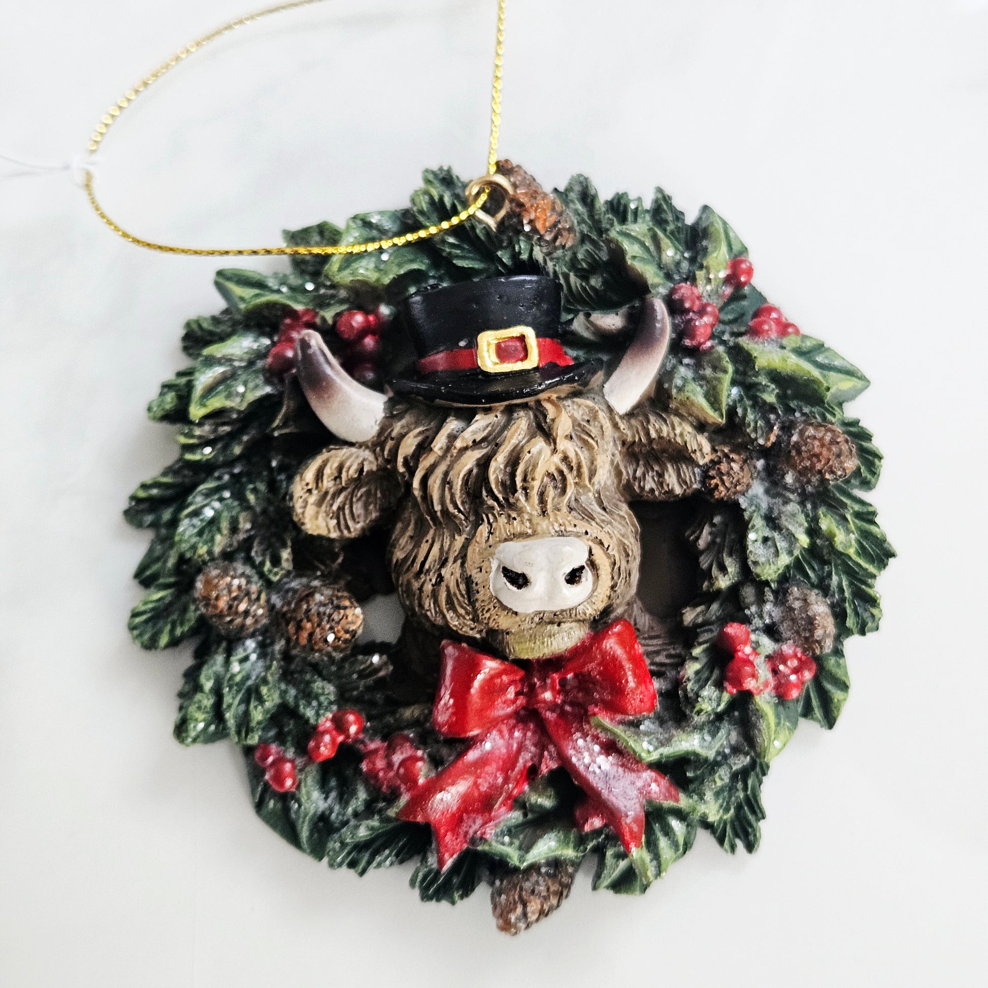 Christmas ornament with a Highland cow in a wreath on a white background