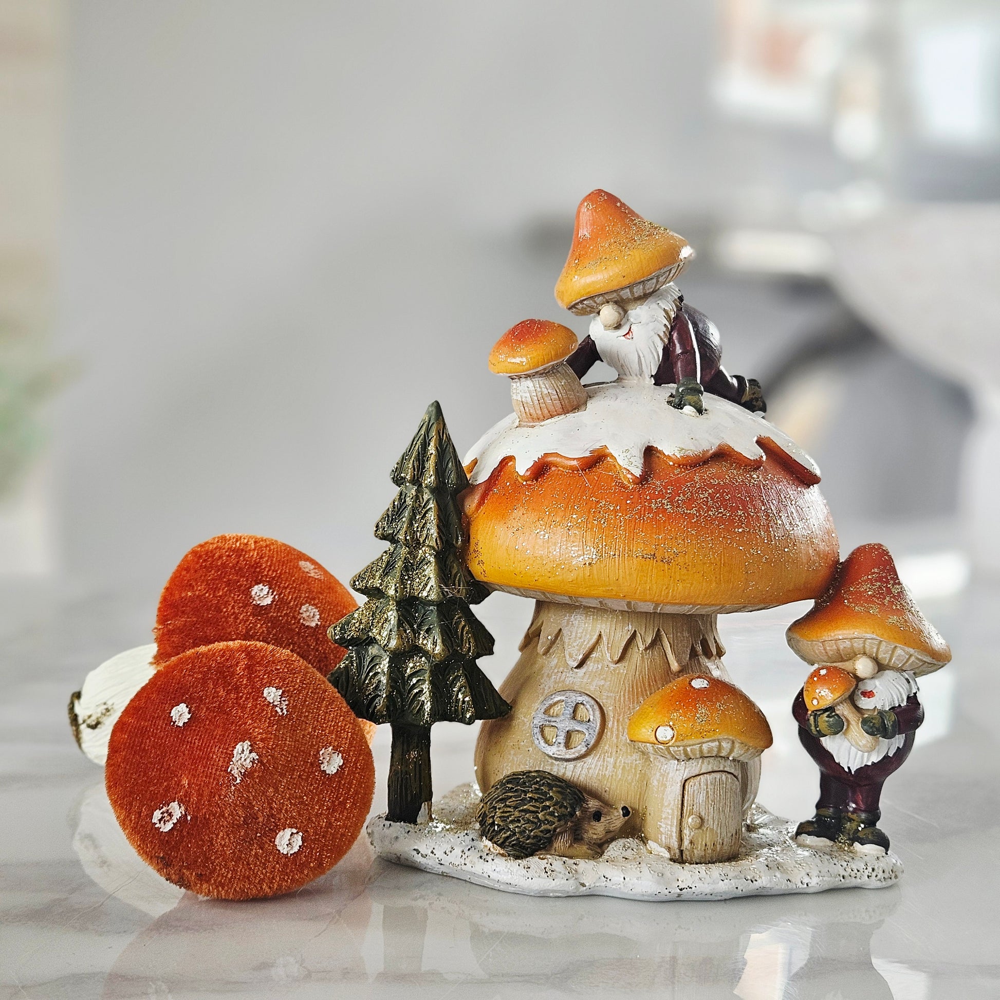 Decorative led figurine with monks, mushrooms, and a hedgehog on a mushroom-shaped house.