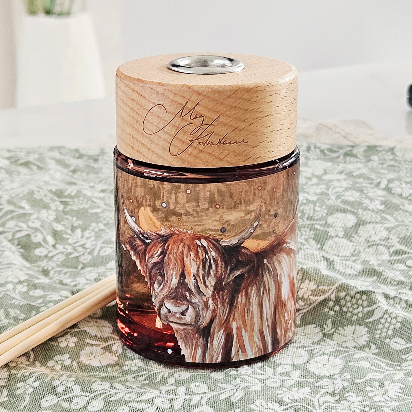 Reed diffuser by meg Hawkins 150ml with wooden lid featuring a highland cow illustration scent apple orchard