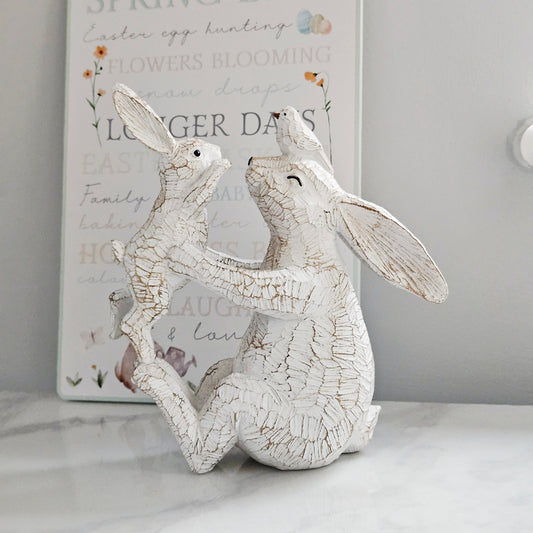 Decorative white rabbit figurine holding a baby rabbit and bird on mums head
