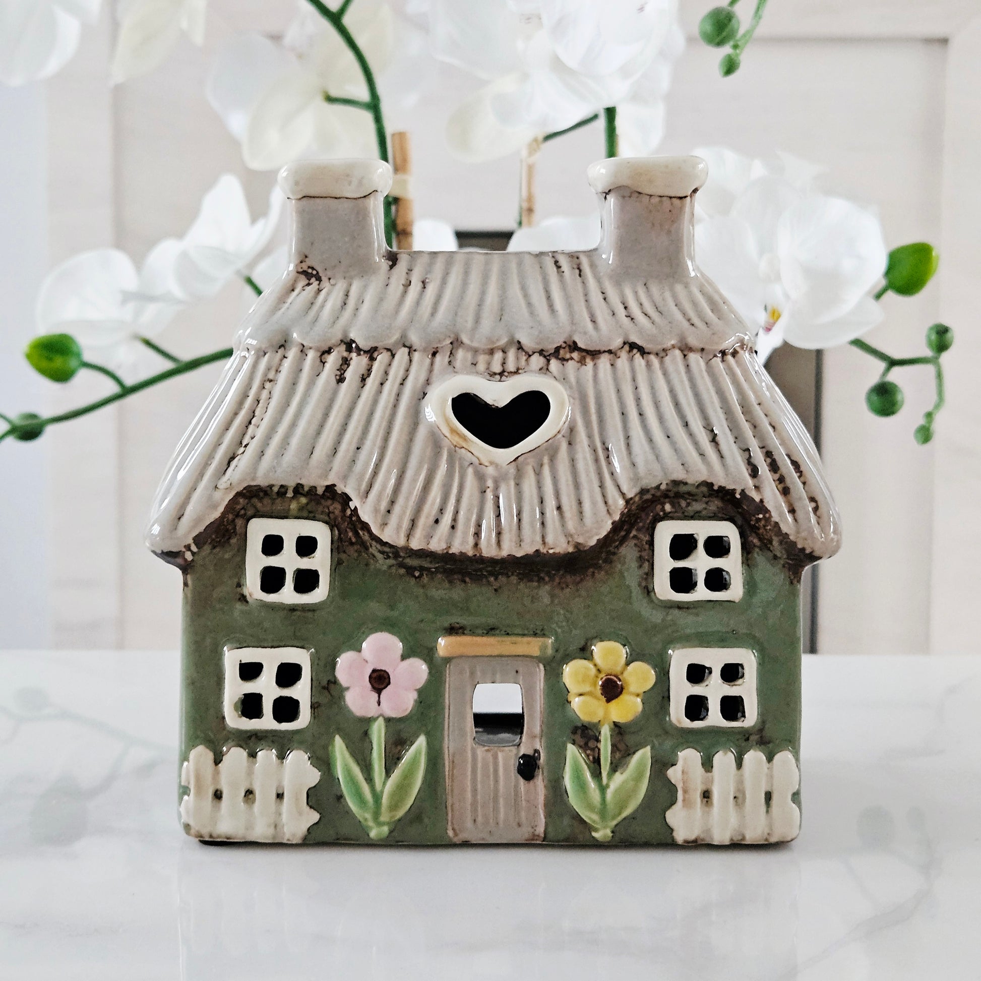 stoneware green house-shaped tea light holder with a heart window and floral decorations