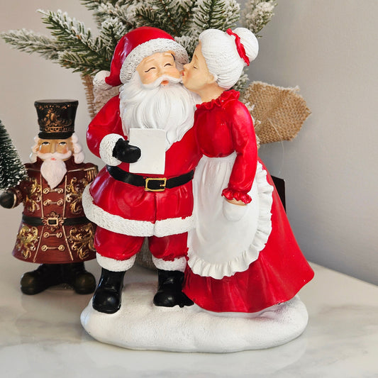 Mr and Mrs Claus Christmas figurine kissing in traditional red and white outfits