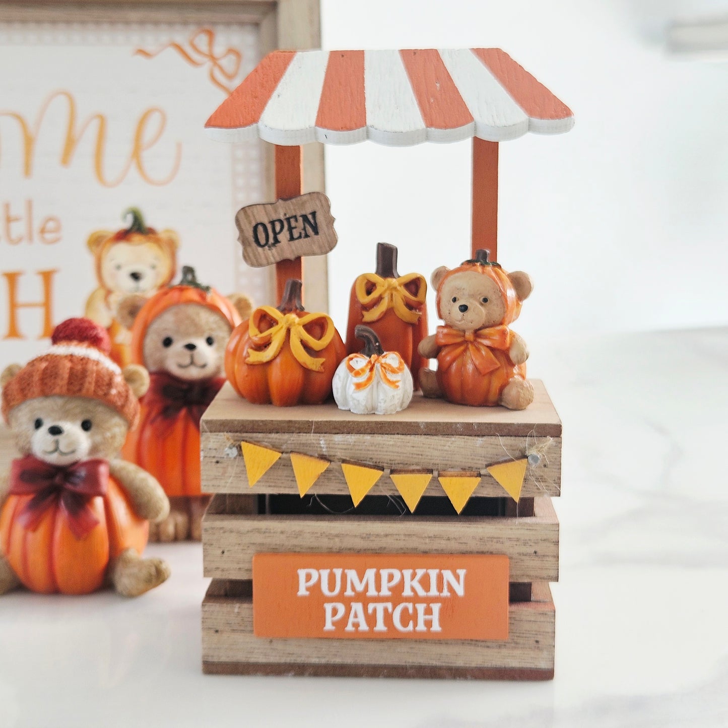 A decorative autumn market stall figurine with a striped awning, small pumpkins, teddy bears dressed as bears, yellow bunting, and a sign reading 'PUMPKIN PATCH' and 'OPEN'.