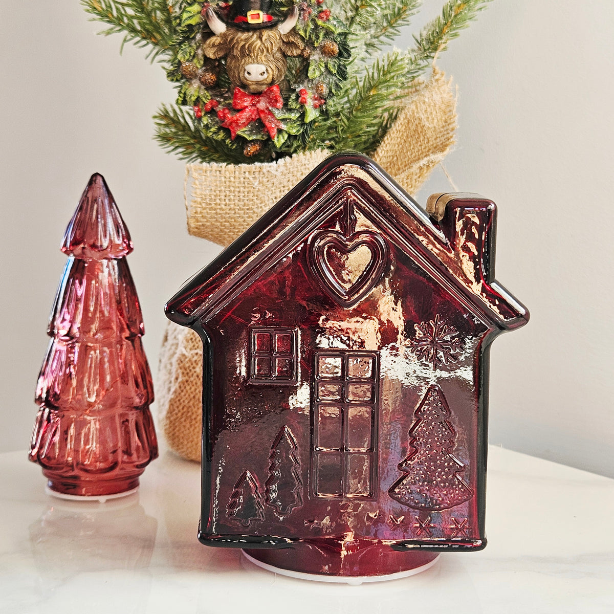 A glossy dark red glass led gingerbread house-shaped ornament with embossed holiday details, 